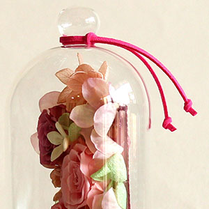 トップに、アクセントカラーのフェイクレザーリボンを結んでお届けします。