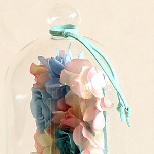 トップに、アクセントカラーのフェイクレザーリボンを結んでお届けします。