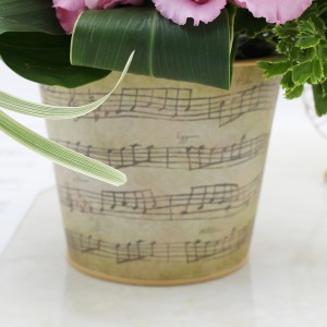 ピンクの花々を音符が描かれたベージュの花器にあしらいました。